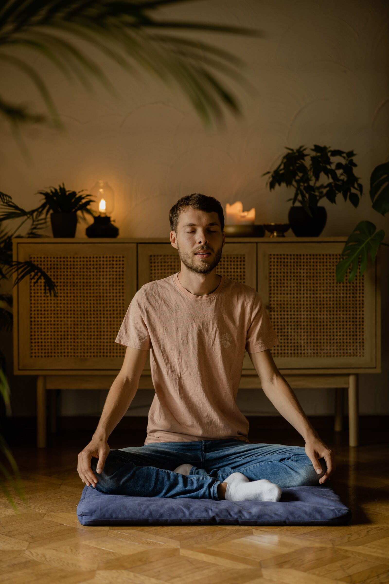 Heinz in Meditation, frontal, rosa Kerzen auf dem Sideboard.
