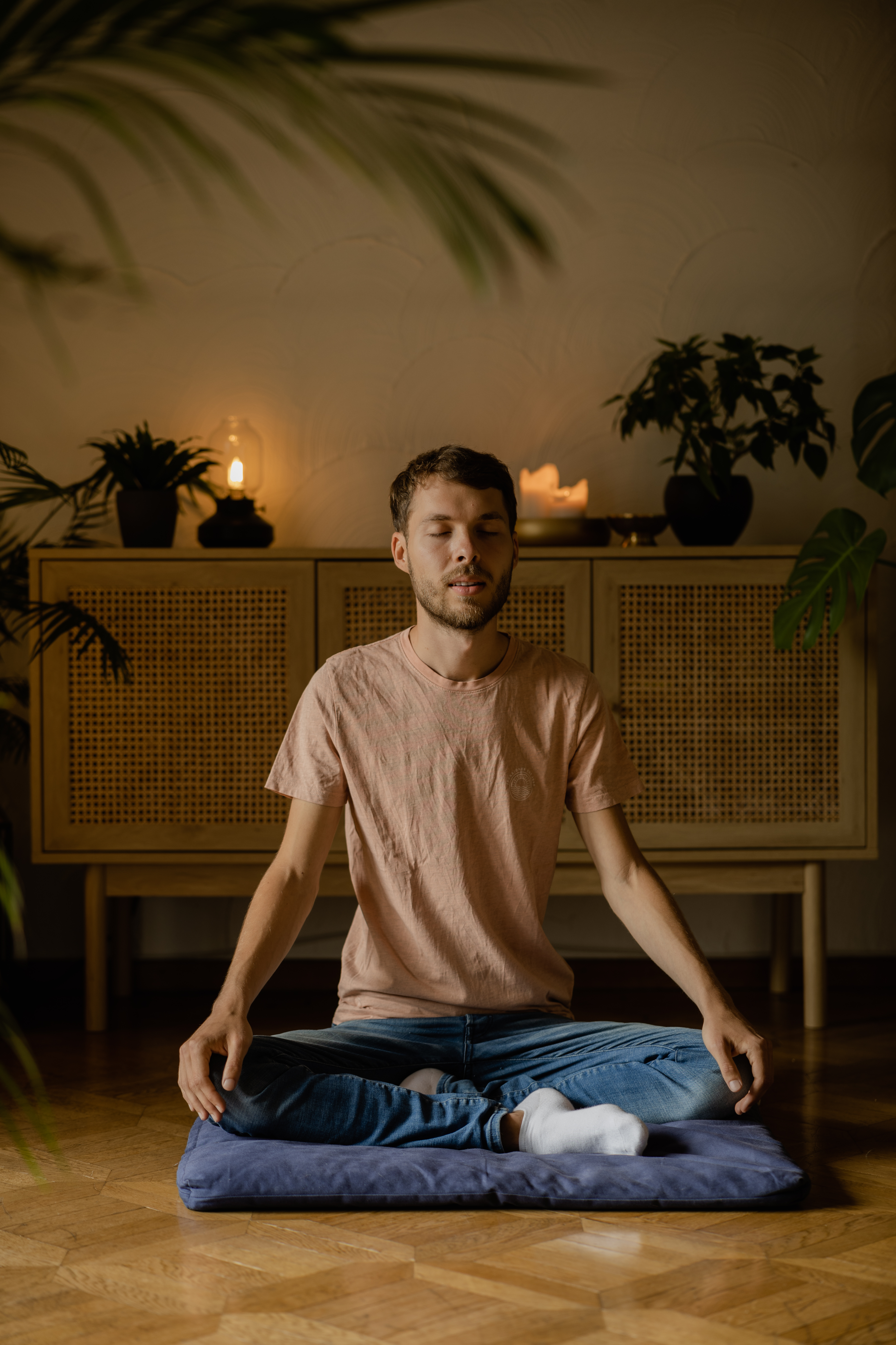 Heinz in Meditation, frontal, rosa Kerzen auf dem Sideboard.