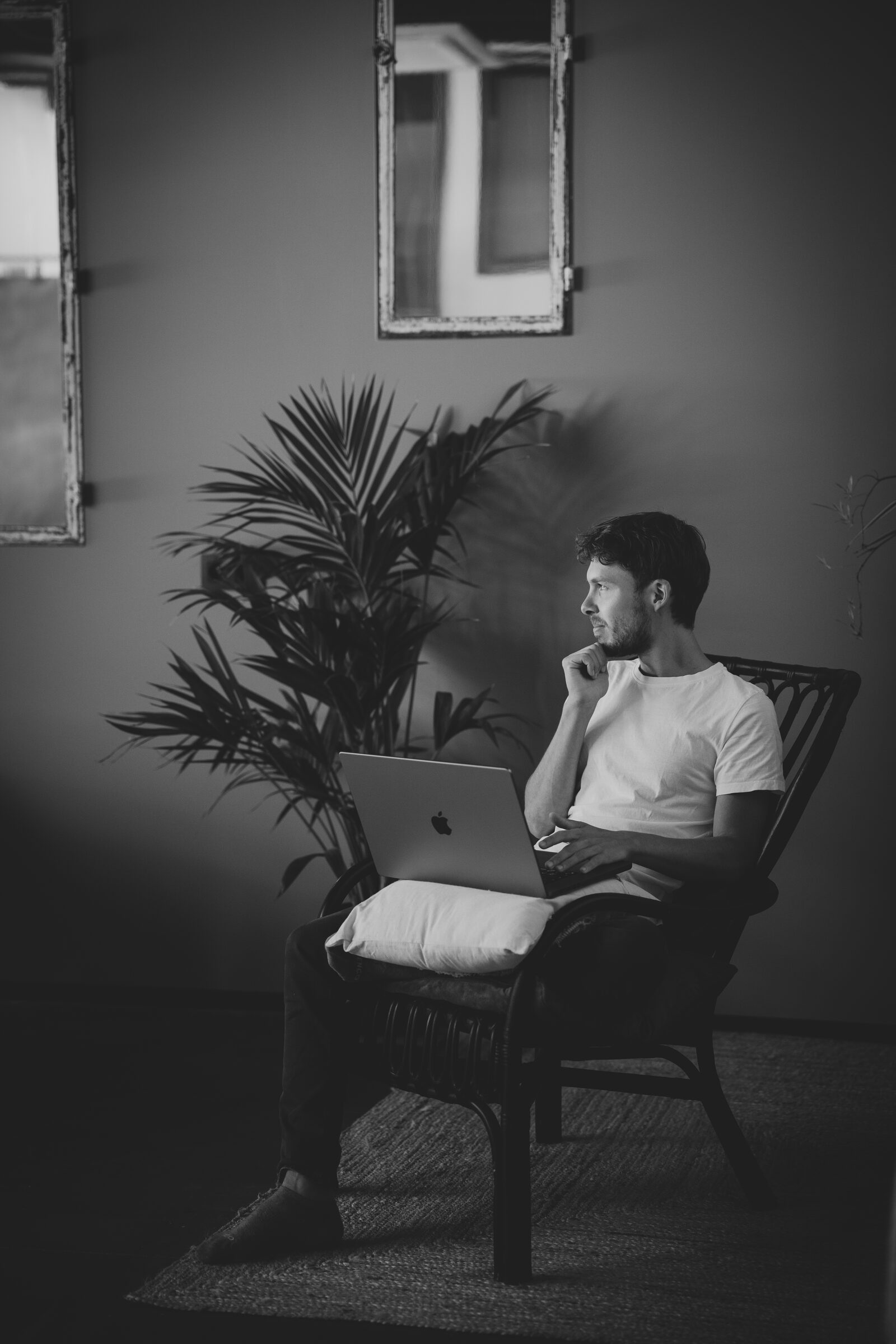 Heinz sits in an armchair in front of his laptop, black and white, looking to the side, light falling in from the window.