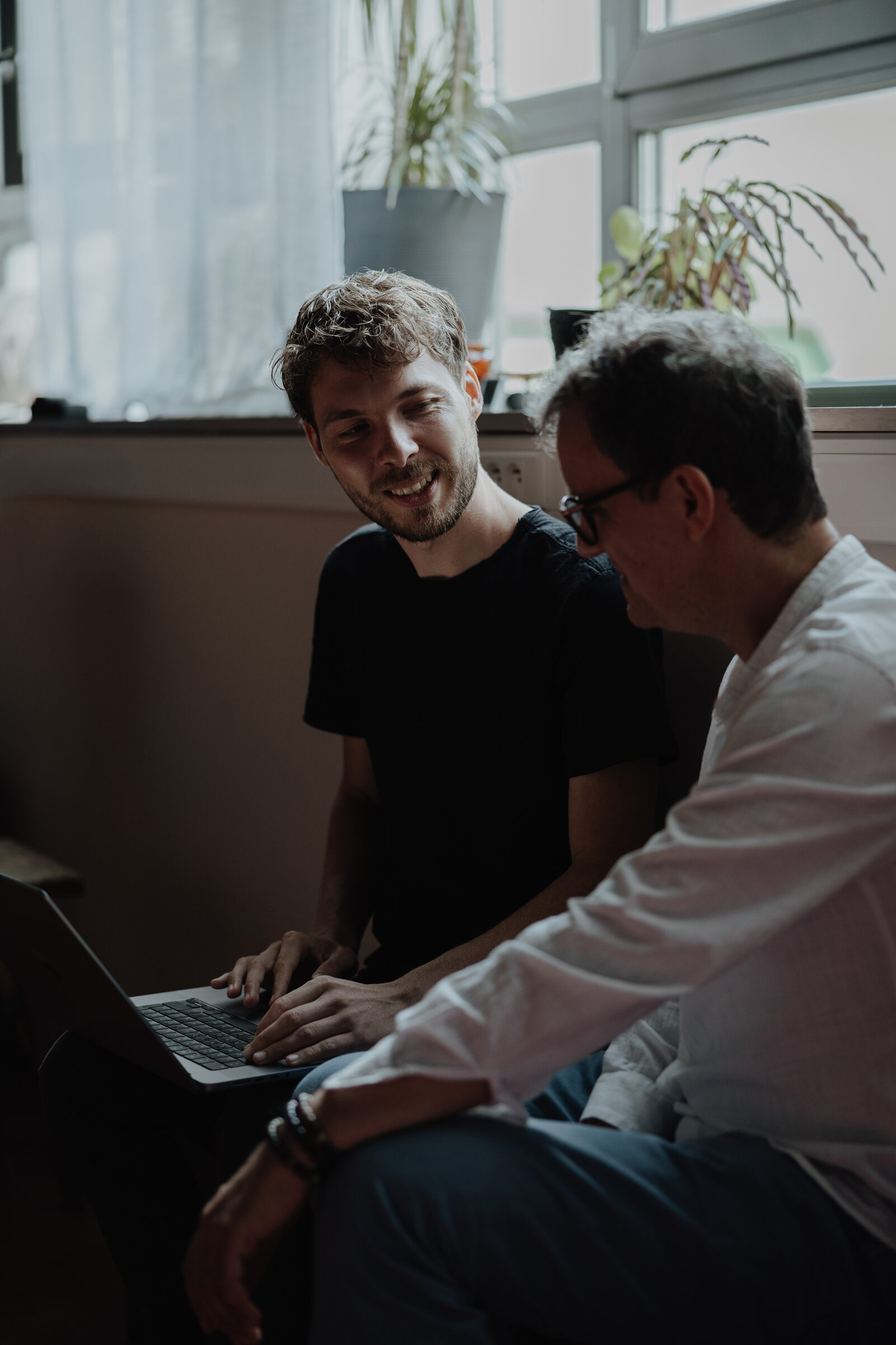 Heinz and a client together at the laptop by the window, Heinz smiling as he explains.