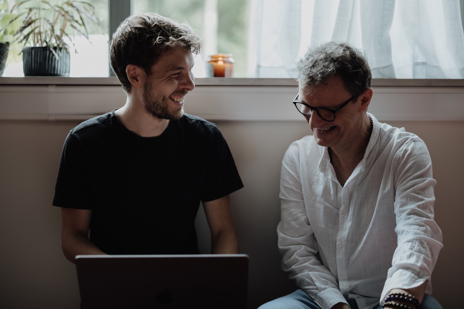 Heinz and a client side by side at the laptop, laughing, turned toward each other.